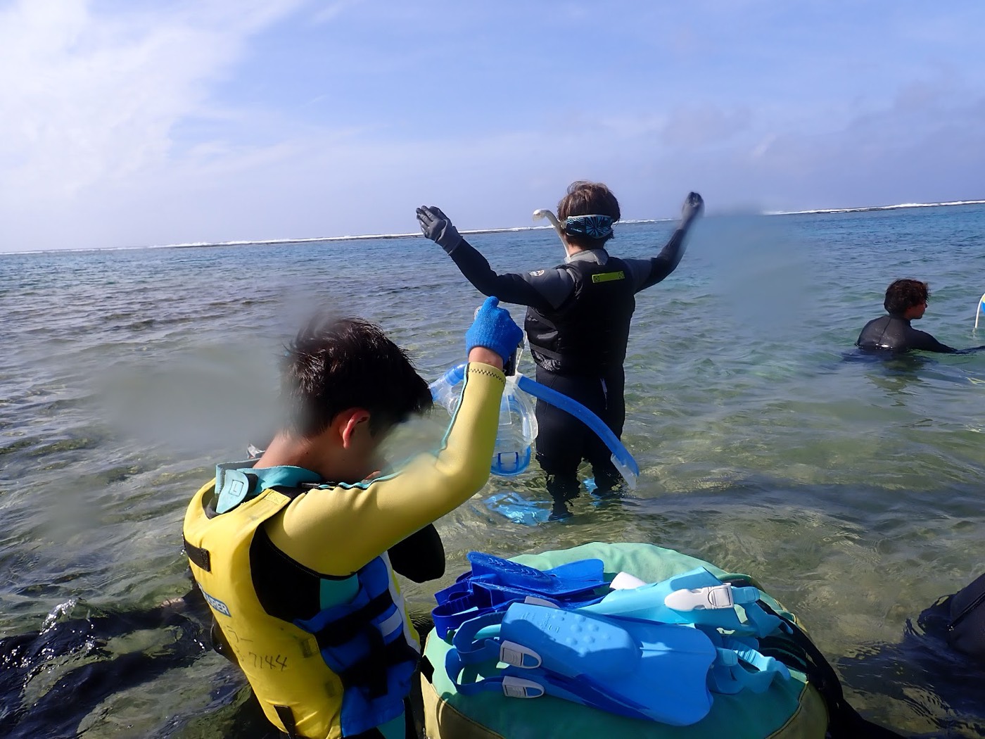 天然水族感で紹介する、浅瀬でシュノーケル器材のマスクやフィンを装着し、海に入る準備をする参加者