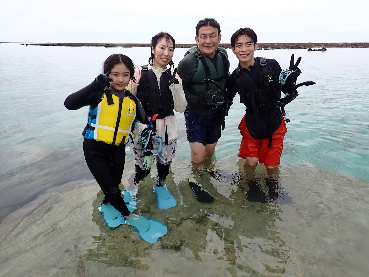 浅瀬でライフジャケットを着用した参加者が笑顔で写真撮影に応じる