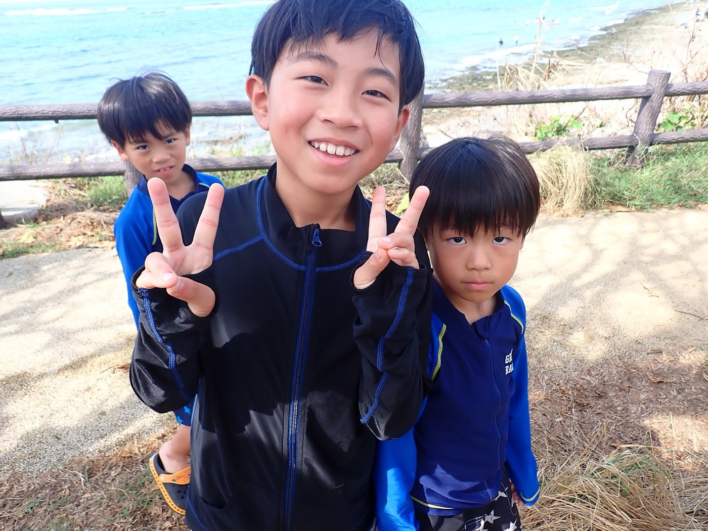 海岸を背景に、小さなお子様を含むグループが並んでピースサインをしている