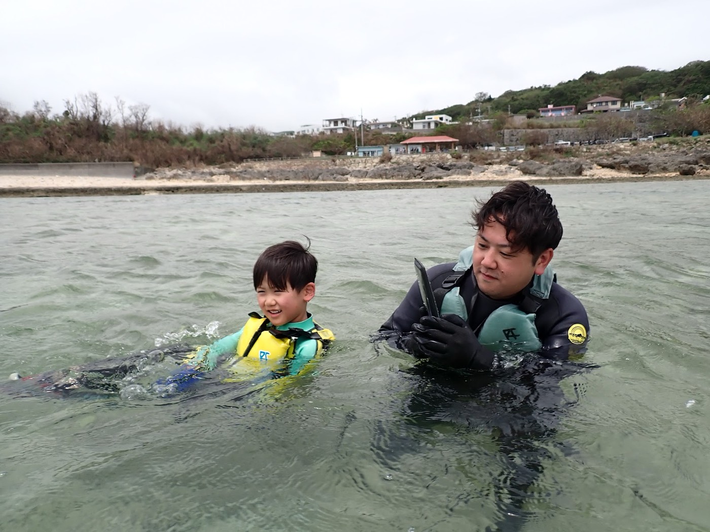 水中で担当の池田と小さなお子様が笑顔で触れ合っている風景