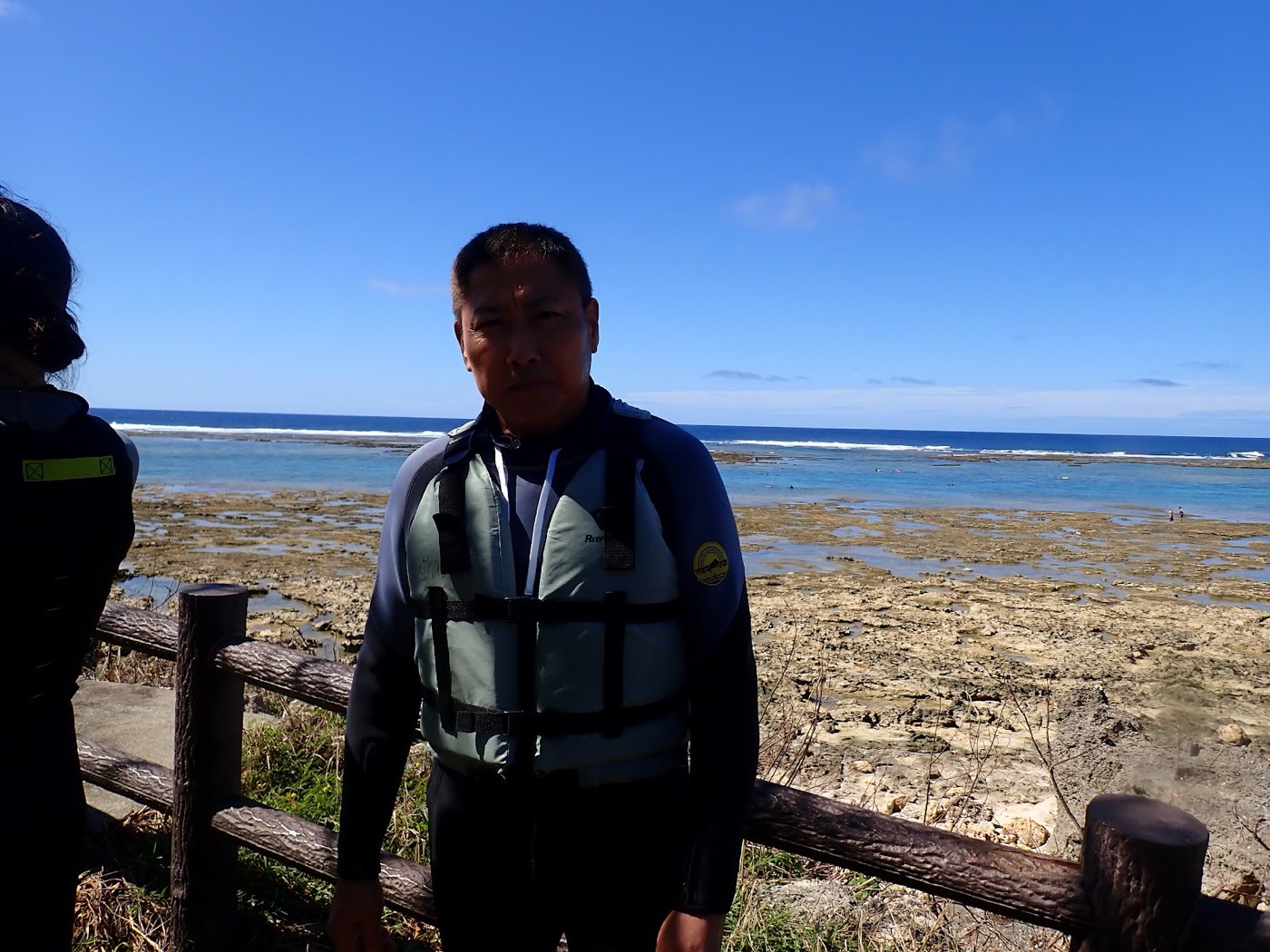 ライフジャケットを着けたガイドがビーチで準備を整える様子、まるで天然水族感あふれる海を背にしている