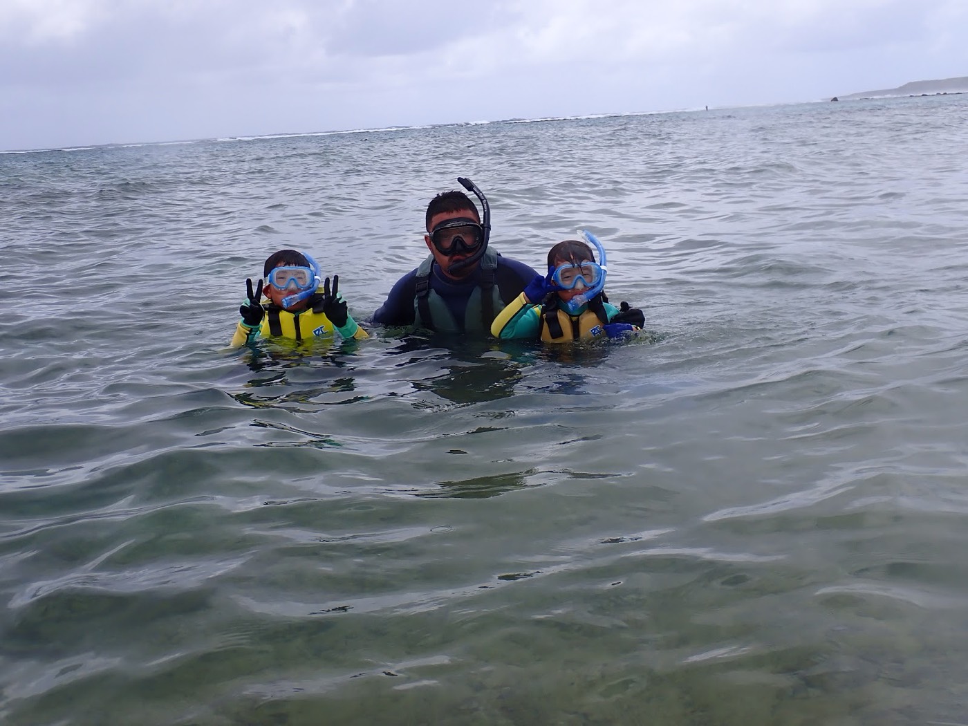 浅い海でガイドと子どもたちがマスクをつけて海を眺める様子