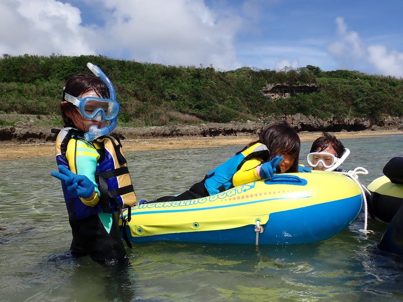 天然水族感で紹介する、天然水族館の浅瀬で青い浮き輪につかまり、Vサインで笑顔を見せる子供たち