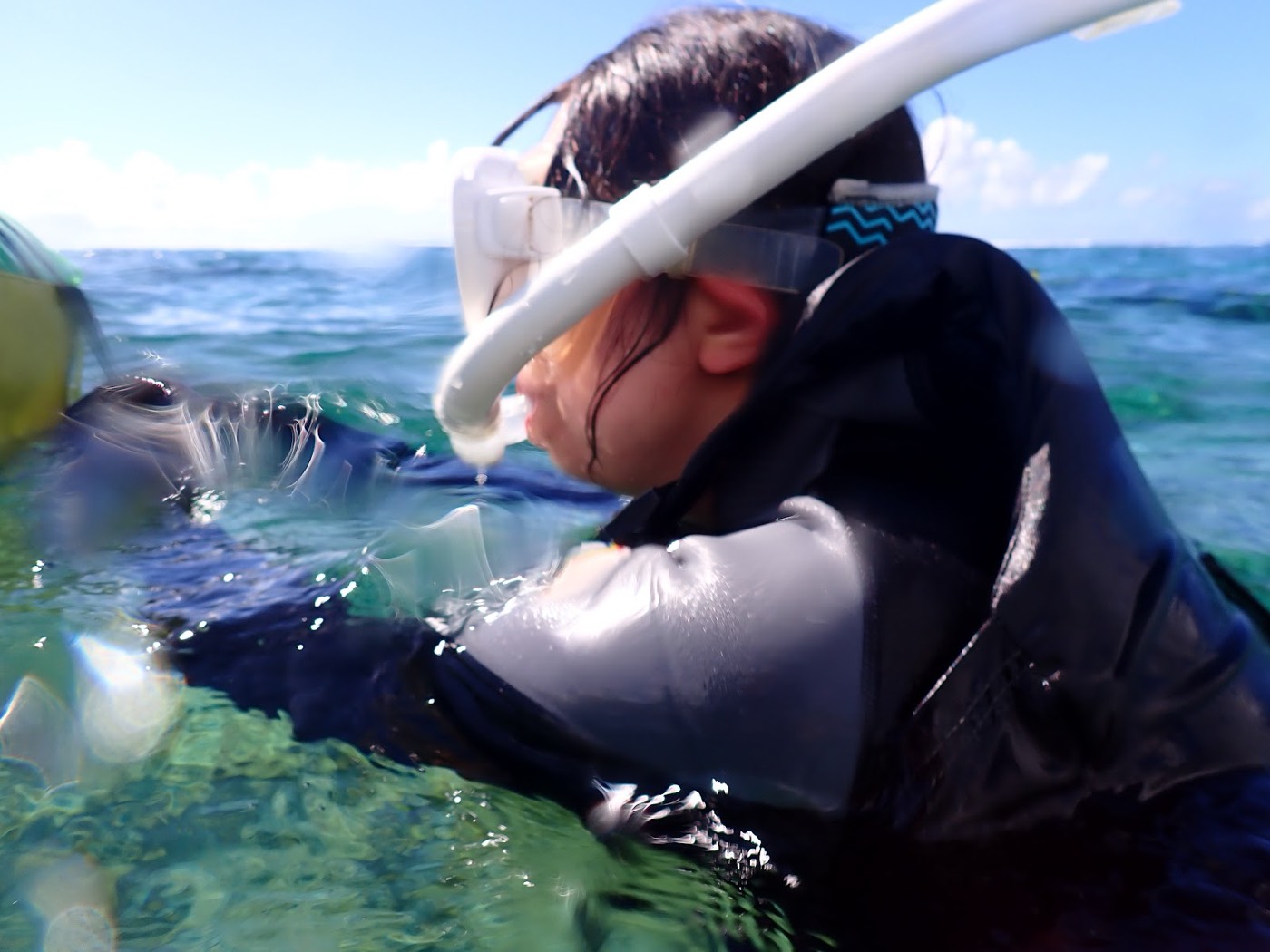 シュノーケルマスクをつけ、水面に浮きながら海を眺める子供の横顔